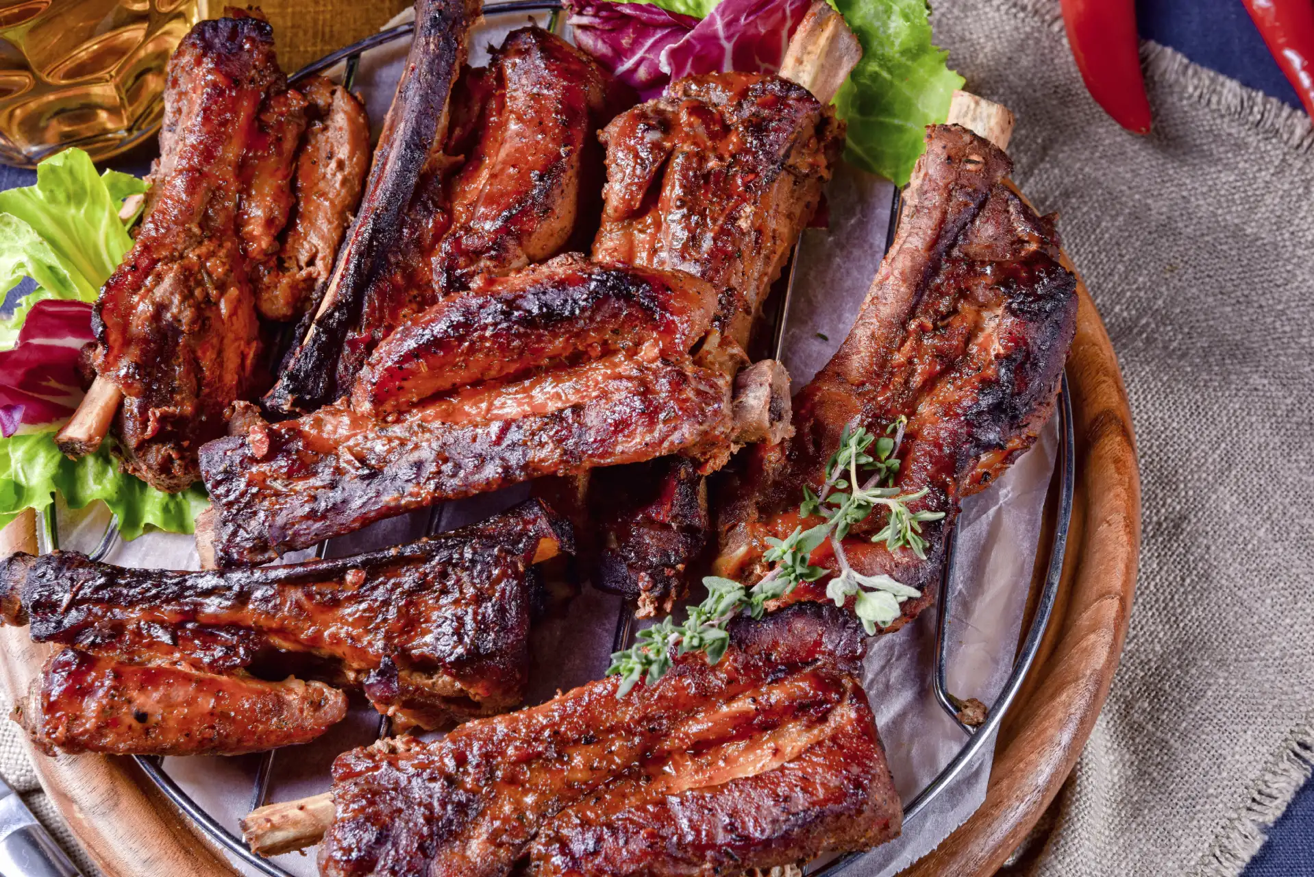 Servierte gebräunte Spareribs mit würziger Glasur, Salatblättern und Kräutern auf einem Teller